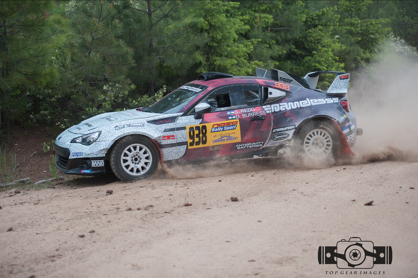 a subaru brz rally car kicking up dust as it passes by