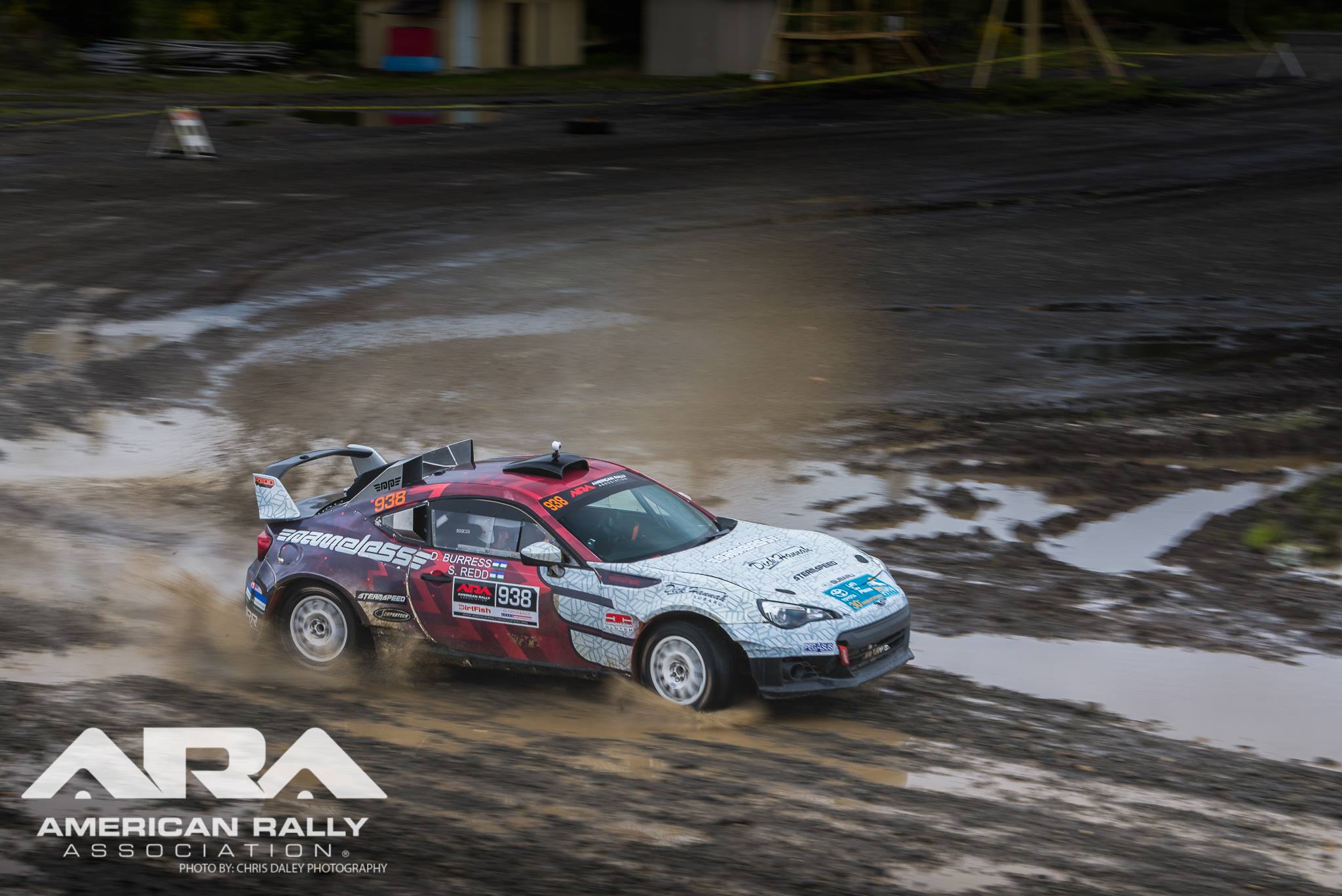 a subaru brz rally car sliding through a very wet course