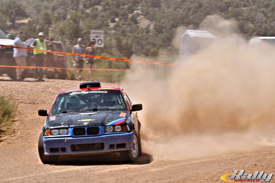 a BMW rally car sliding sideways on a gravel road