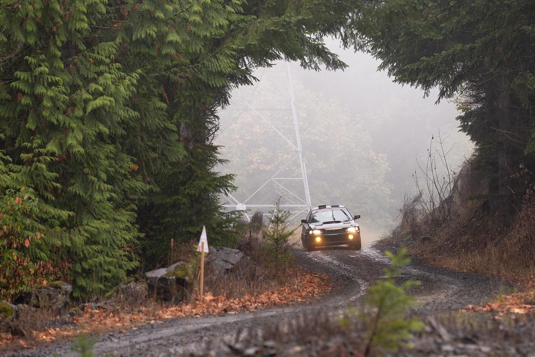 a dark green rally subaru in a clearing in the trees on a wet day